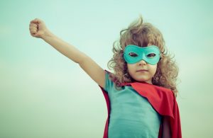 young girl dressed in superhero costume with arm outstretched