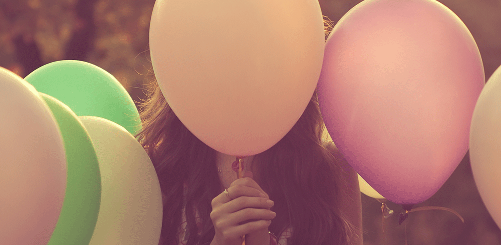 girl holding a balloon in front of her face