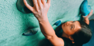 close focus on lady's hand on a rock climbing wall at gym